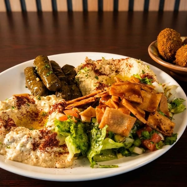 A platter of Middle Eastern appetizers including hummus, stuffed grape leaves, salad, and falafel.